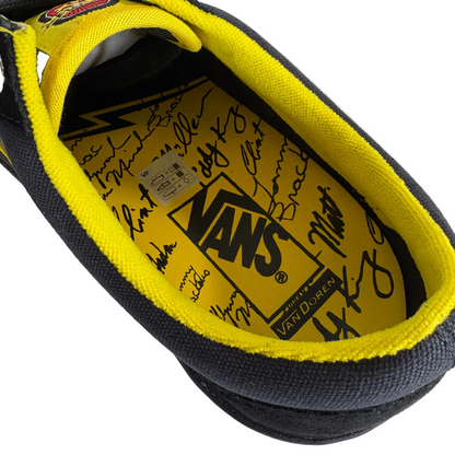 Close-up of a Vans shoe with yellow lining and signature text on a white background